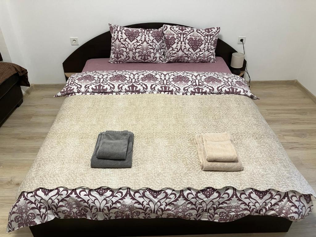 a bed with a black and white comforter and two towels at Апартамент Рая in Devin