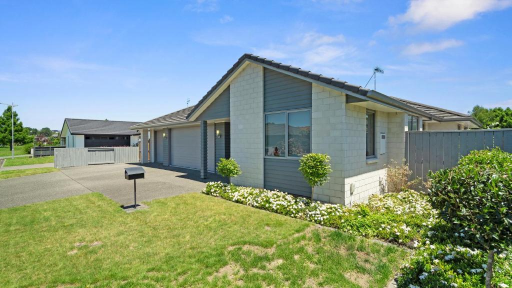 陶朗加的住宿－The Lakehouse - Tauranga Holiday Home，绿色草坪庭院内的房子