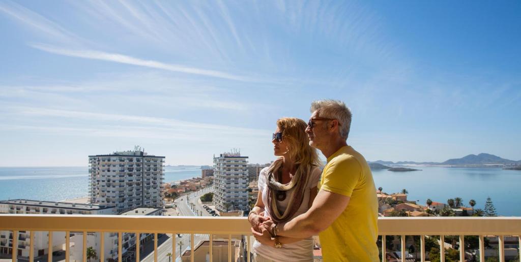 um homem e uma mulher de pé numa varanda com vista para o oceano em Poseidon La Manga Hotel & Spa - Designed for Adults em La Manga del Mar Menor