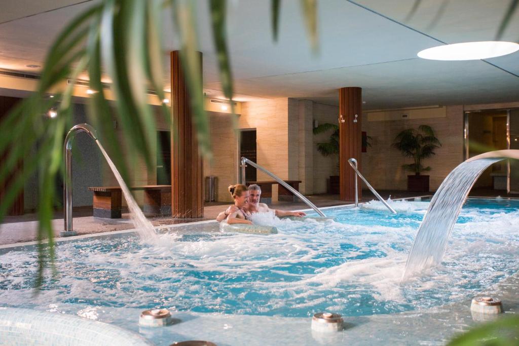 2 personas en una bañera de hidromasaje en una piscina en Poseidon La Manga Hotel & Spa - Designed for Adults, en La Manga del Mar Menor