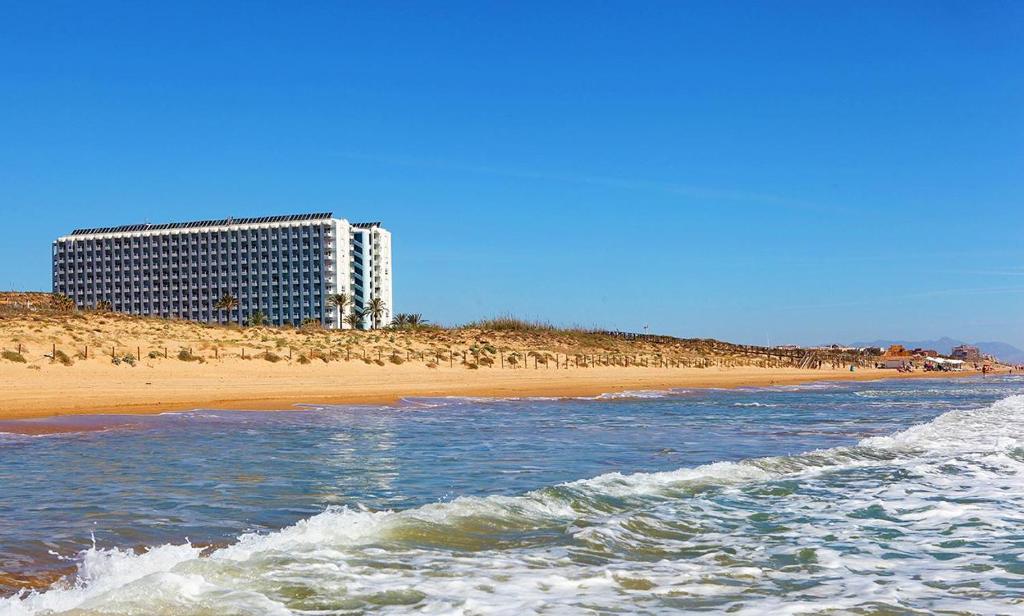 a view of a beach with a building in the background at Hotel Playas de Guardamar in Guardamar del Segura