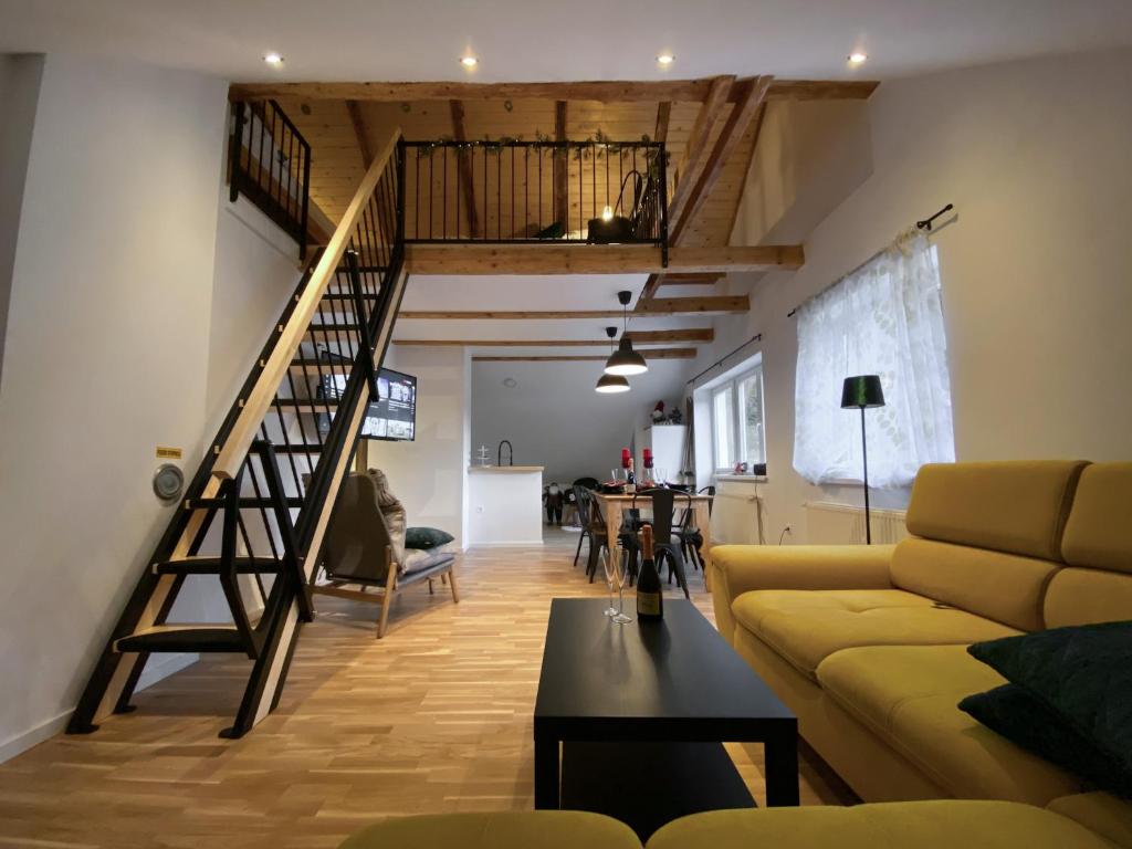 a living room with a staircase and a yellow couch at Apartments Gozdni Raj Rogla in Oplotnica