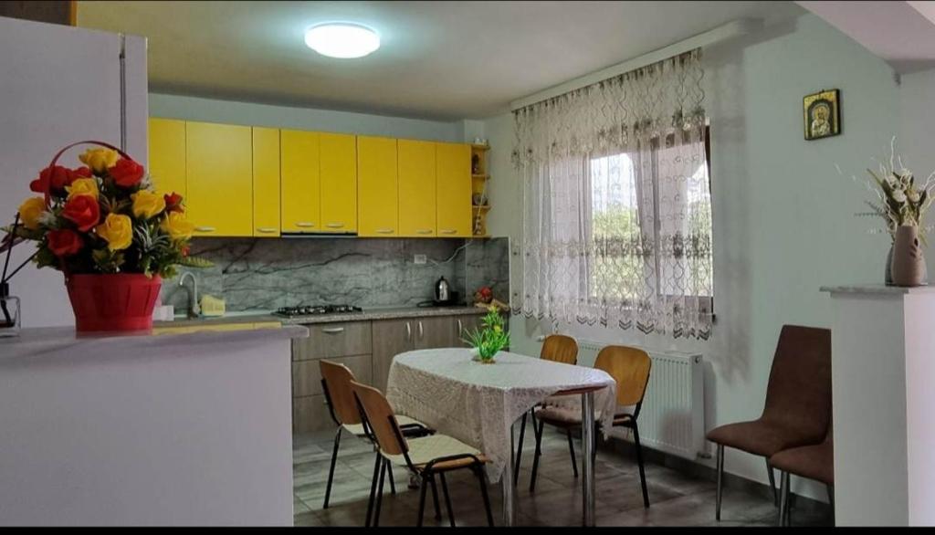 eine Küche mit gelben Schränken sowie einem Tisch und Stühlen in der Unterkunft CASA ROTARU in 2 Mai