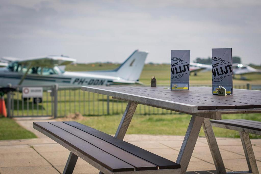 een houten picknicktafel met twee dozen en een vliegtuig bij De Vlijt Business class suite in De Cocksdorp