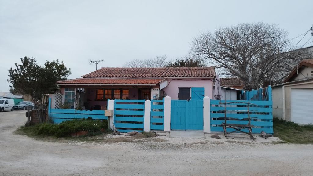 uma cerca azul em frente a uma casa em UNE MAISON SUR UNE PRESQU'ILE em Port-Saint-Louis-du-Rhône