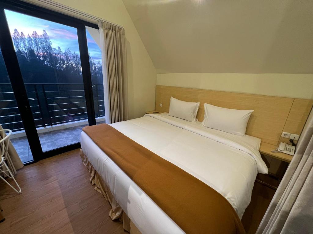 a bedroom with a large bed and a large window at Hotel Nature Bromo and Resort in Pasuruan