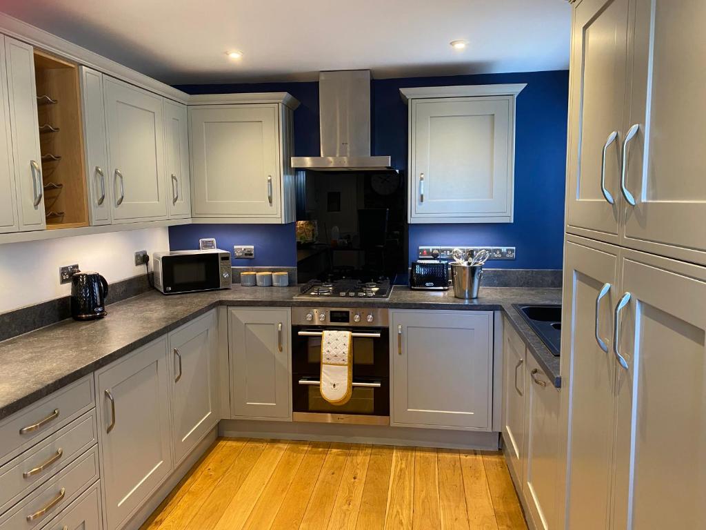 a kitchen with white cabinets and a stove top oven at Foxy cottage nr Westward Ho! in Northam