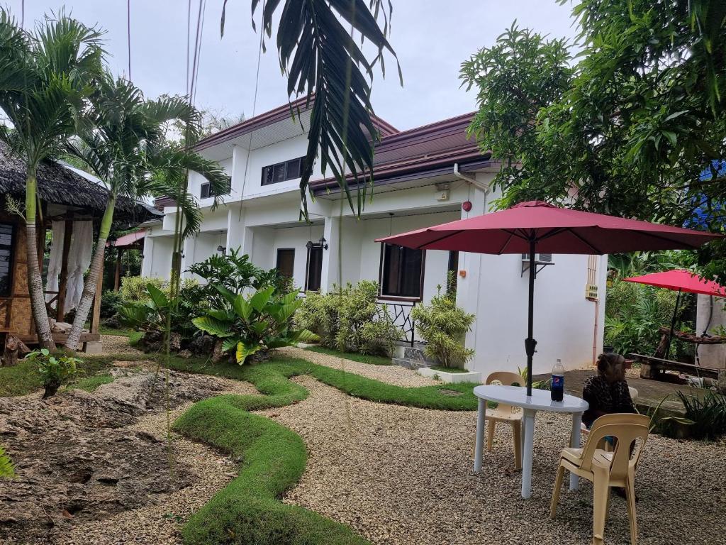 邦勞的住宿－Mannah Garden Staycation Place，房屋前的桌椅和遮阳伞