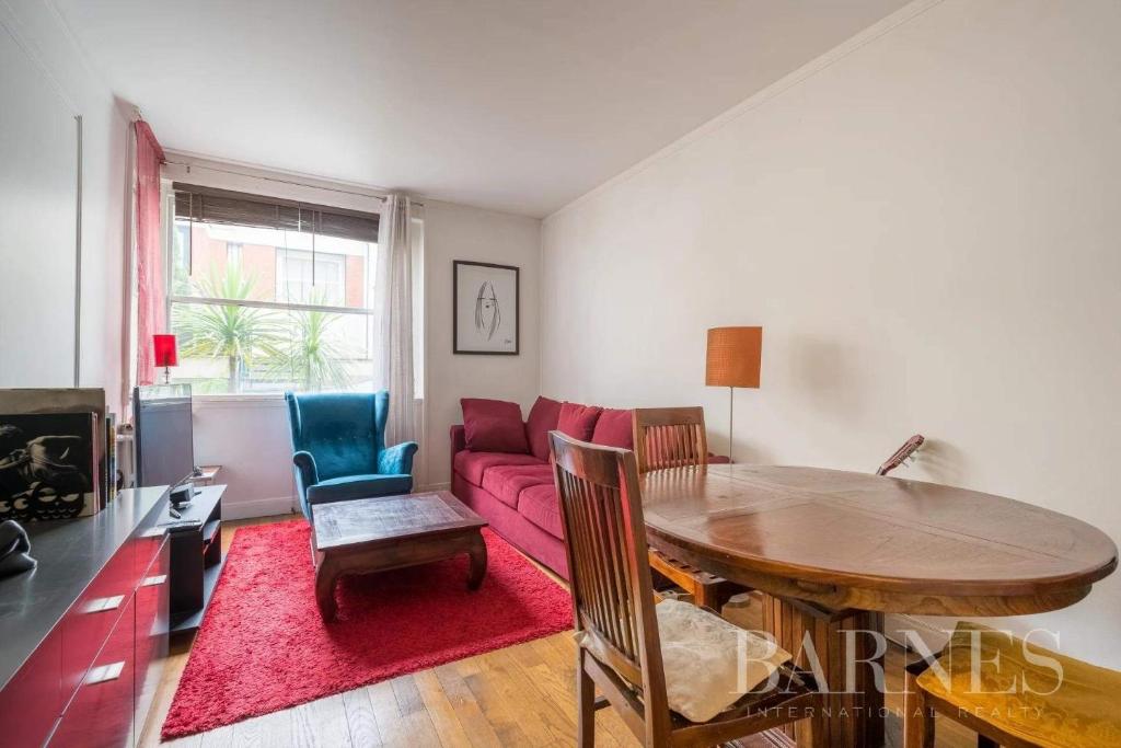 - un salon avec une table et un canapé rouge dans l'établissement Neuilly-Sur-Seine f2 en rez de chaussée, à Neuilly-sur-Seine