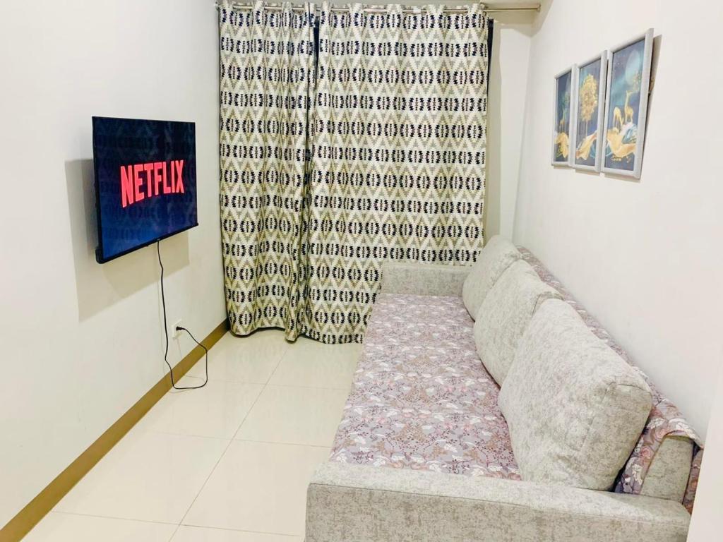 a living room with a couch and a curtain at Sea Residences, S, Shell Janine's Residency in Manila