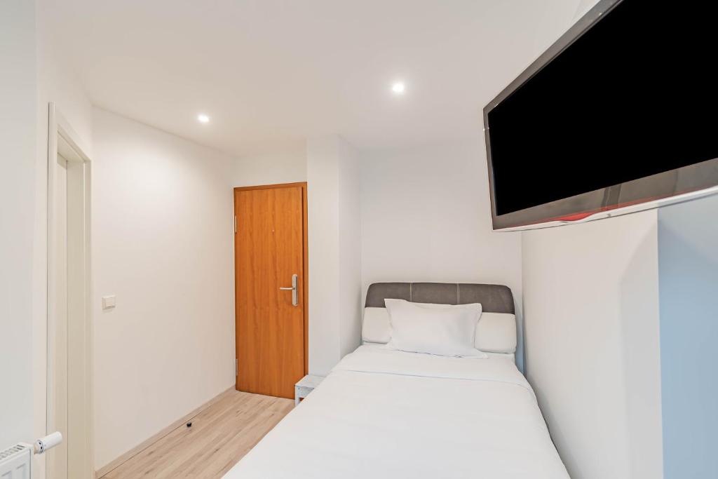 a small bedroom with a bed and a flat screen tv at Hotel Herckmans in Ettelbruck