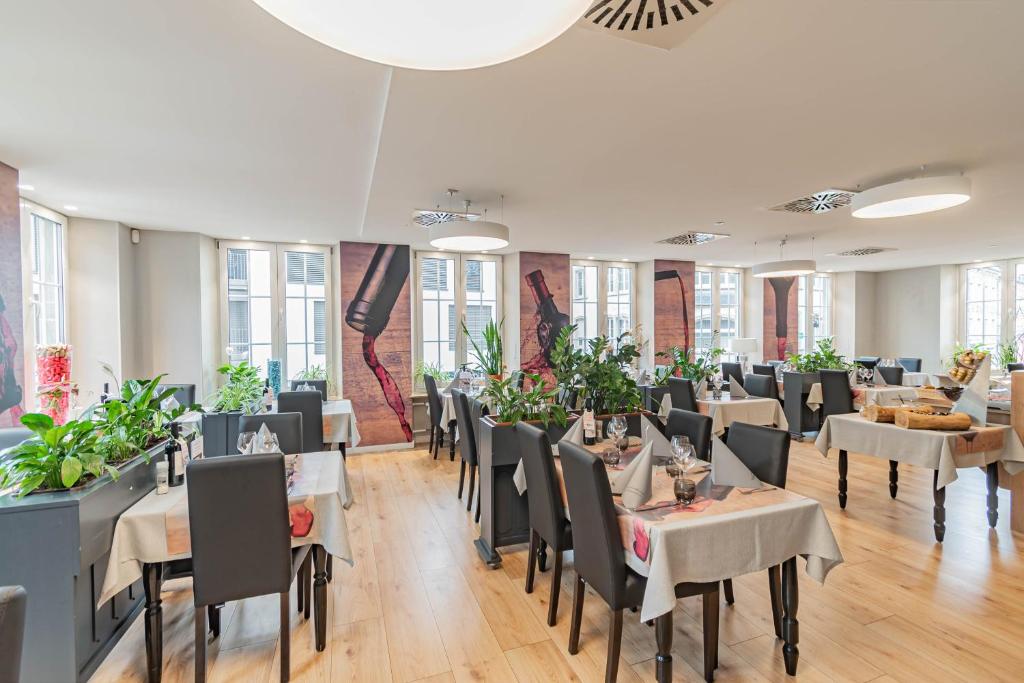 a dining room with tables and chairs and windows at Hotel Herckmans in Ettelbruck