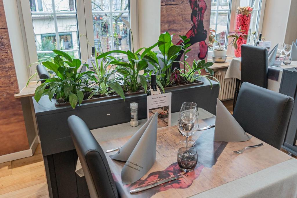a table with glasses of wine and plants on it at Hotel Herckmans in Ettelbruck
