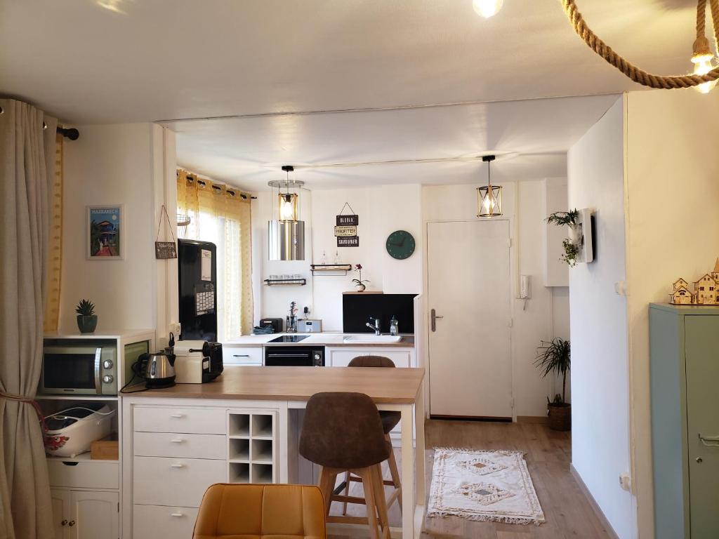 eine Küche mit weißen Schränken sowie einem Tisch und Stühlen in der Unterkunft Maison du Bonheur 2 à TROYES Logement entier avec parking in Troyes