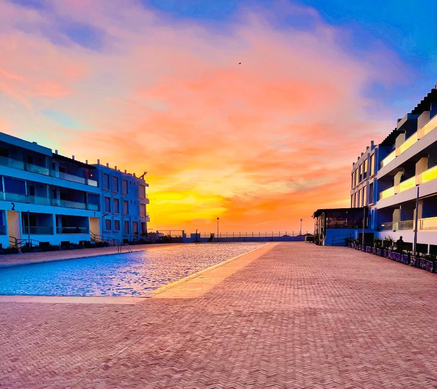 an empty street with buildings and a sunset in the background at The blue pearl-Sensational beach apartment in Aourir in Agadir