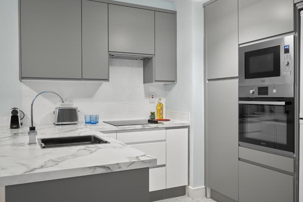 a white kitchen with a sink and a microwave at Luxury Apartment near O'Connell Street in Dublin
