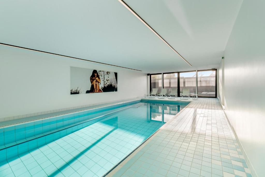 a swimming pool in a building with a large window at Villa Paradis - De ultieme kustvilla met zwembad ! in Koksijde