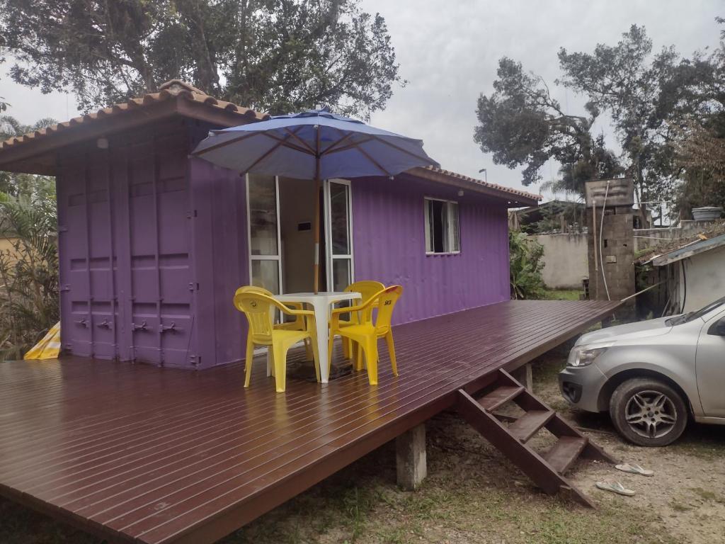 uma casa roxa com uma mesa e cadeiras num deque em Kitnet contêiner climatizada em Ubatuba
