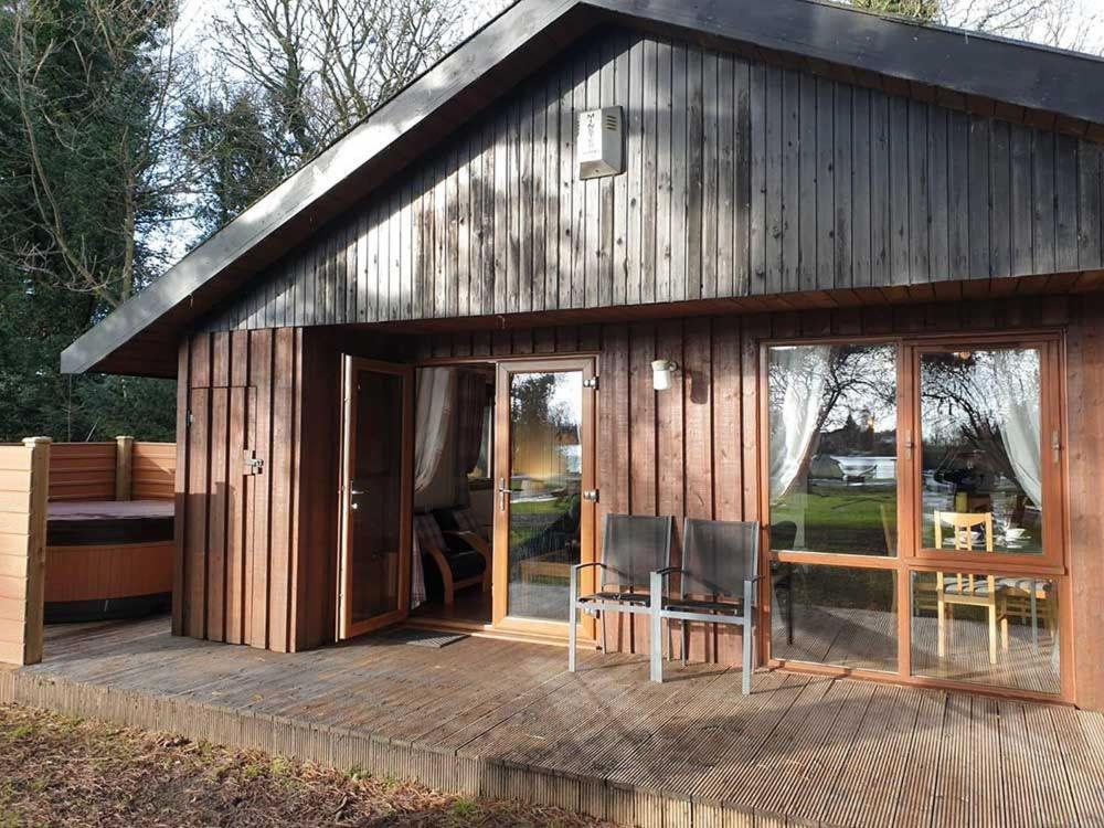 Cabaña de madera con 2 sillas en una terraza en Willow Lodge 13 Hot Tub en York