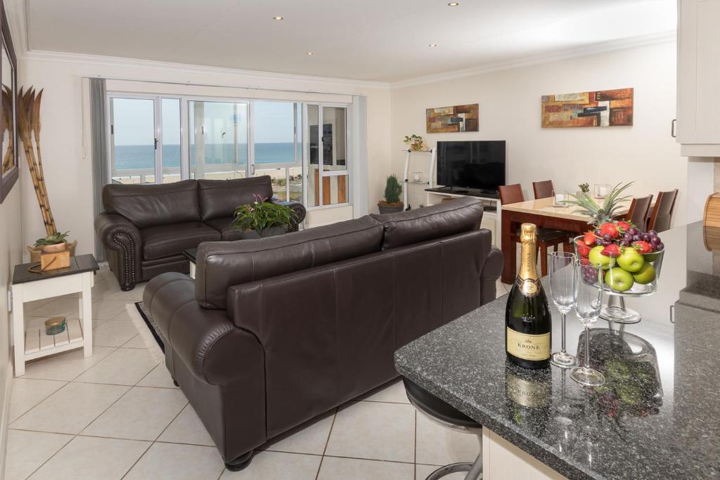 a living room with a couch and a table with a bottle of wine at Main Beach Penthouse in Jeffreys Bay