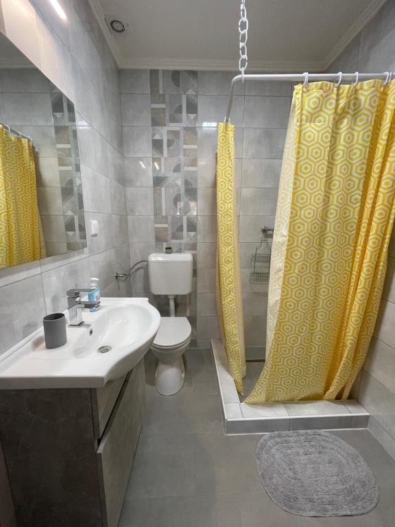 a bathroom with a sink and a yellow shower curtain at Dóra Vendégház in Csongrád