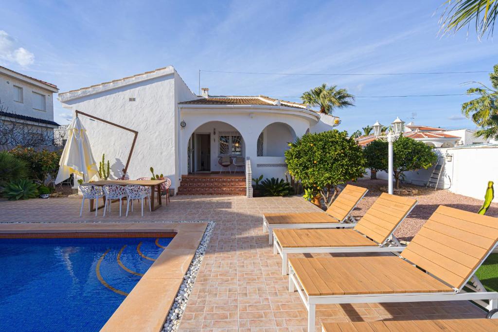 a villa with a pool and chairs and a house at Casa Velazquez in Rojales