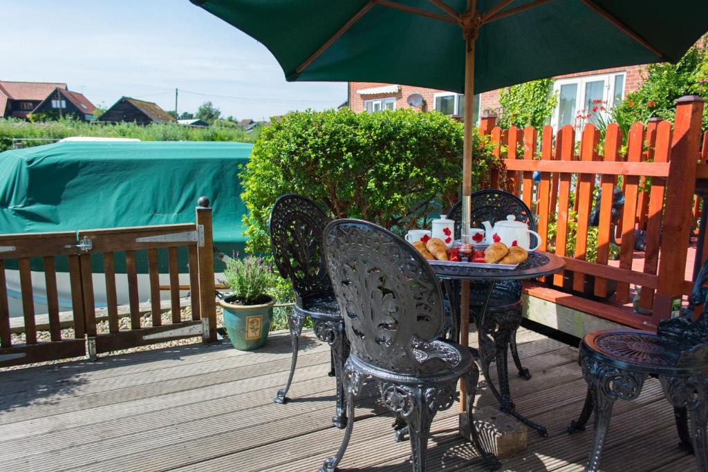 a table and chairs with an umbrella on a deck at Quayside Cottage - Norfolk Holiday Properties in Wroxham