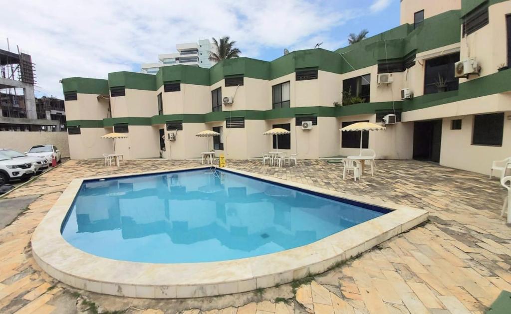 a swimming pool in front of a hotel at Apartamento Vilage na Praia de Armação Salvador in Salvador