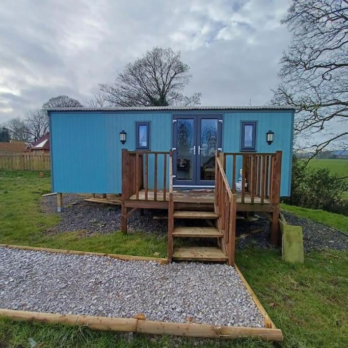 a blue tiny house with a porch and two benches at The Shepherd's Delight in Rushton Spencer