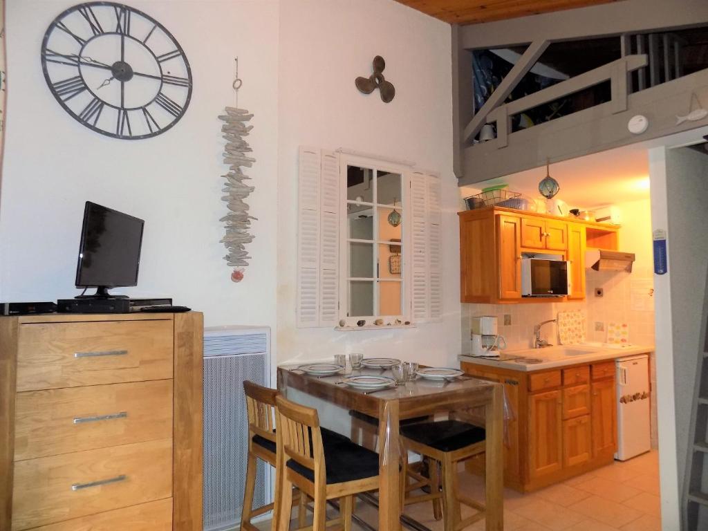 eine Küche mit einem Holztisch und einer Uhr an der Wand in der Unterkunft La Palmyre - CHARMANTE VILLA MITOYENNE avec TERRASSE CLOSE in Les Mathes