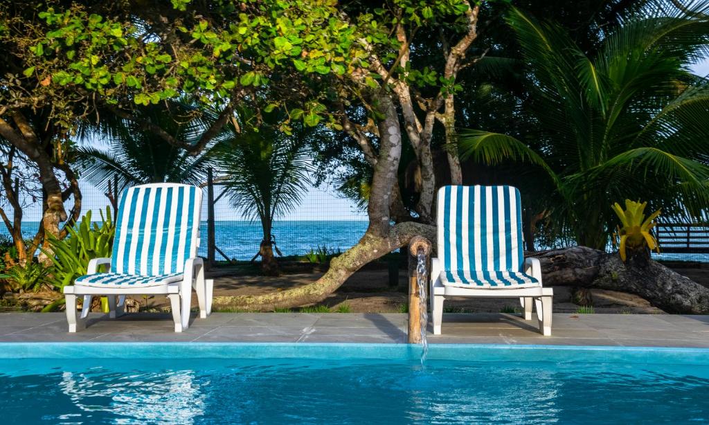 two blue and white chairs sitting next to a swimming pool at Pousada São Francisco in Cumuruxatiba