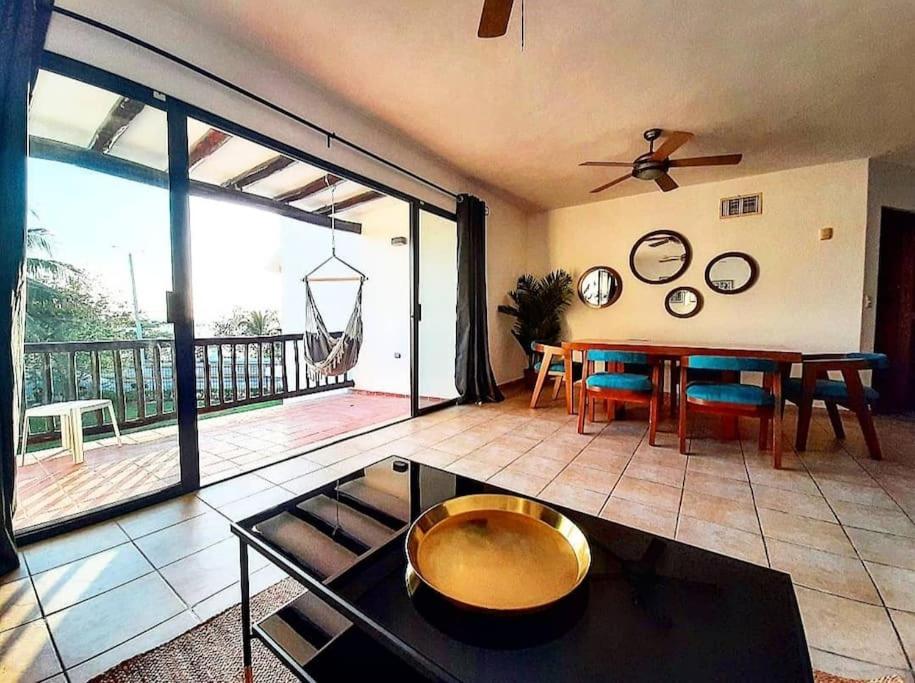 a living room with a table and a balcony at Sunset Condo @ Villas Mayaluum in Cozumel