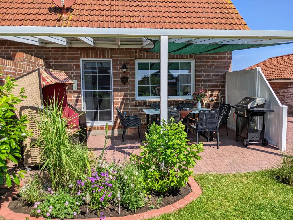 a patio with a grill and a table and chairs at Drei-Insel-Blick Neßmersiel in Neßmersiel