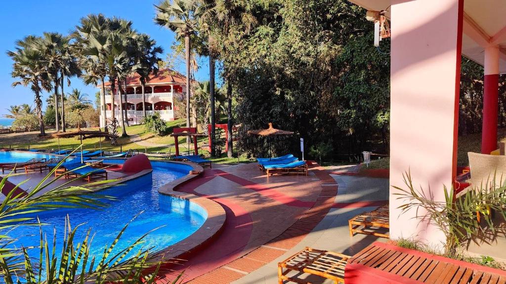 ein Pool in einem Resort mit einem Haus im Hintergrund in der Unterkunft Lemon Creek Hotel Resort in Bijilo