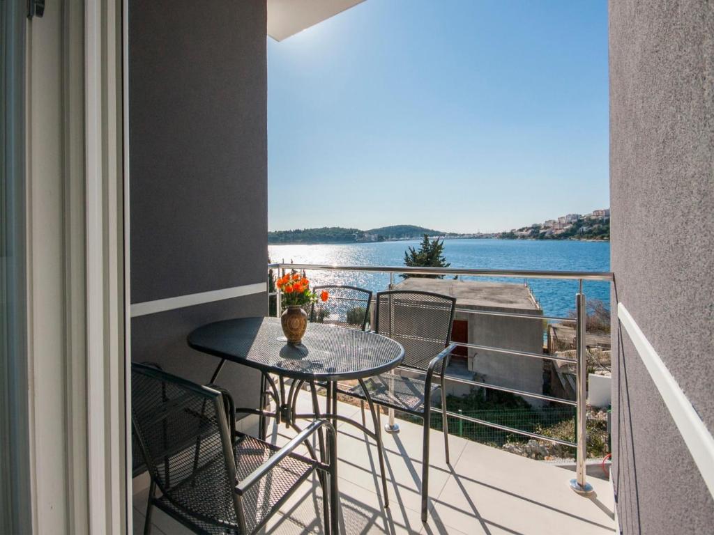 a balcony with a table and chairs and a view of the water at Apartments Happy Holiday in Rogoznica