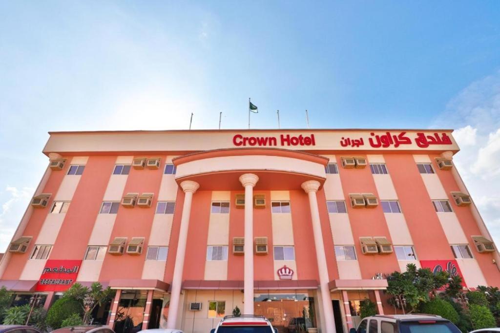 un grand bâtiment rose avec un panneau sur lui dans l'établissement فندق كراون نجران, à Najran