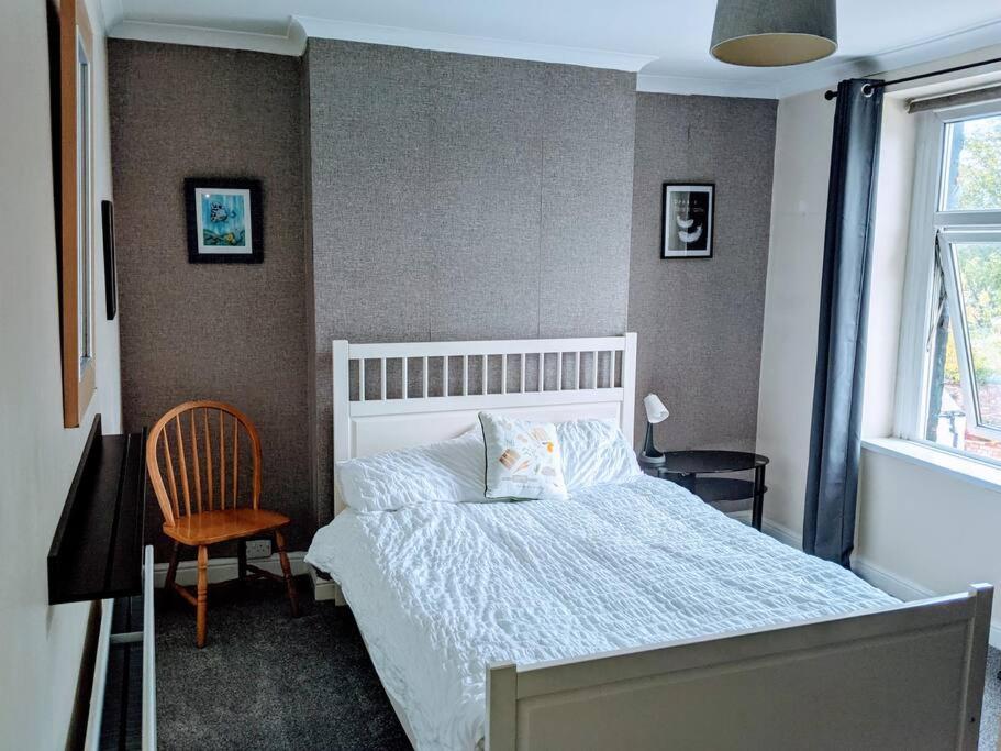 a bedroom with a bed and a chair and a window at Penarth Town Terrace, close to cafes, beaches, Cardiff in Cardiff