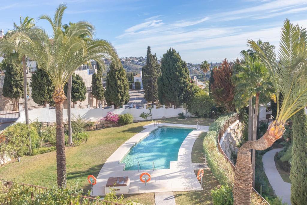 einen Blick über einen Pool in einem Garten mit Palmen in der Unterkunft Sunrise Golf Paradise 1 - Mijas Golf Spain in Mijas