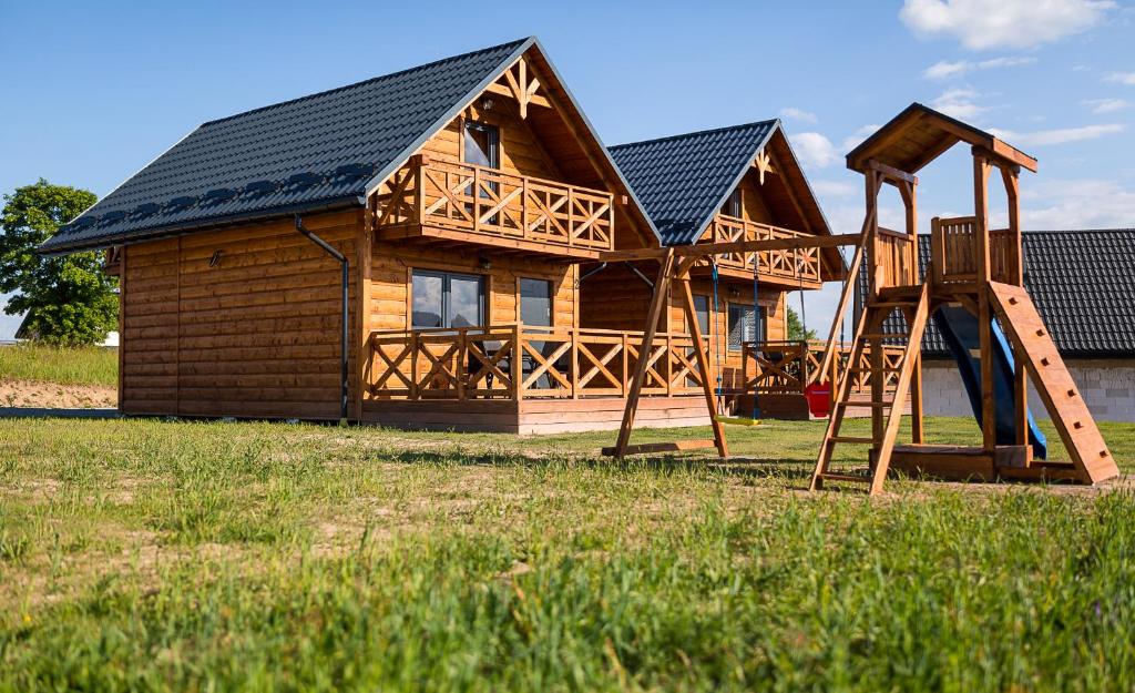 a log cabin with a slide and a playground at Domki w Blasku Słońca in Polańczyk