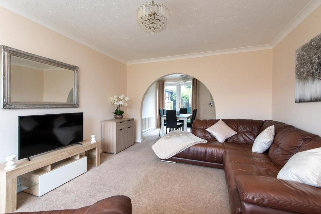 a living room with a brown leather couch and a flat screen tv at Mitford Close in Shincliffe