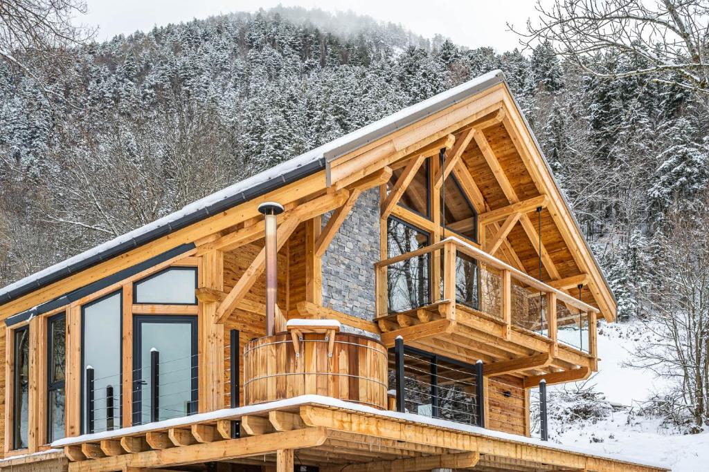 a log cabin with a balcony in the snow at Les chalets d'Éléna in Saint-Jean-Saint-Nicolas