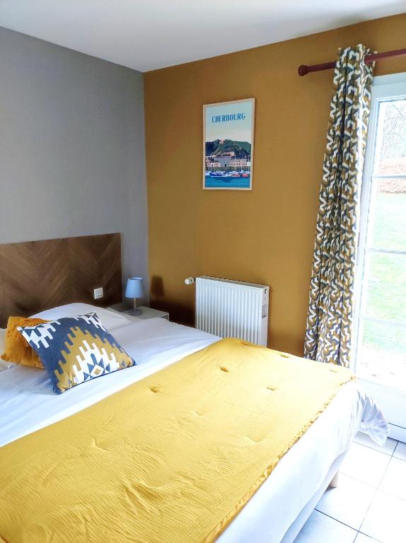a bedroom with a large bed with a yellow blanket at La Minoterie in Tessy-sur-Vire