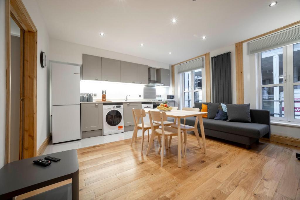 een keuken en een woonkamer met een tafel en stoelen bij Brand new 1Bed Apt - ZONE 1 - 4 Stations Nearby in Londen
