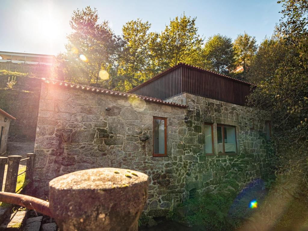 a stone building with a tree stump in front of it at Casa Som do Rio in Ponte de Lima