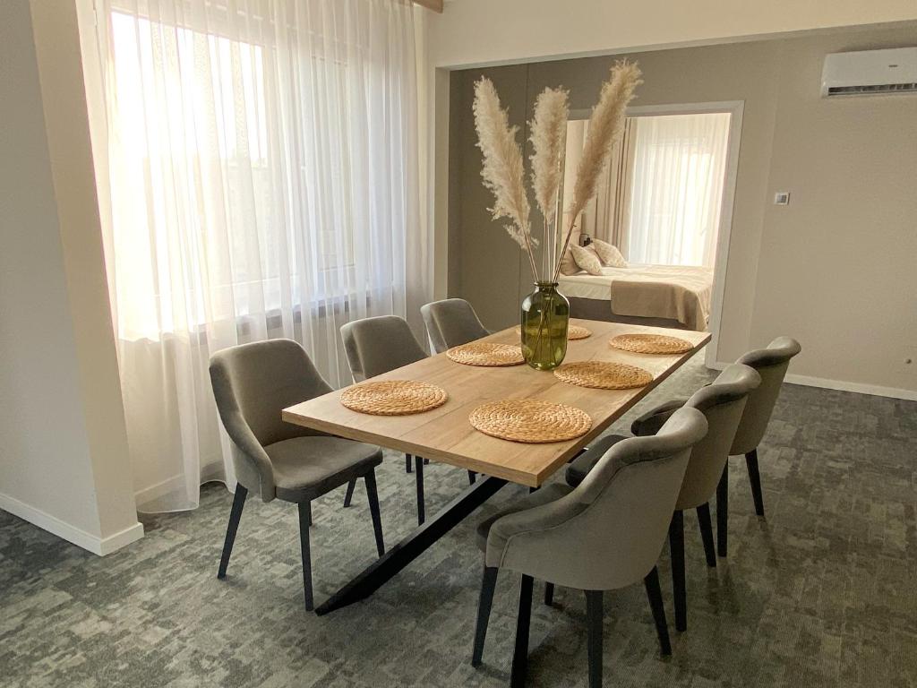 einen Esstisch mit Stühlen und eine Vase mit Blumen in der Unterkunft Apartament Senator 115m2 in Kattowitz