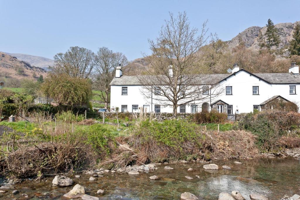 una casa blanca con un río enfrente en No 6 The Forge Coniston, en Coniston