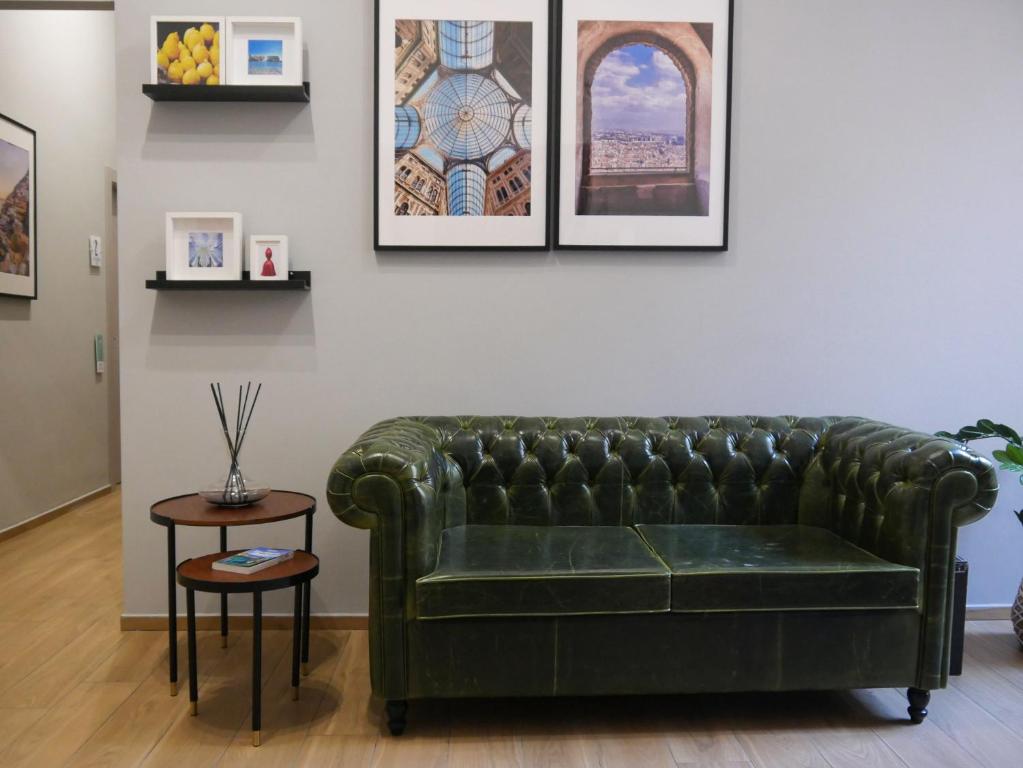 - un canapé en cuir vert dans le salon orné de photos murales dans l'établissement Palazzo Ferrara 1952, à Naples