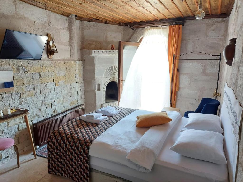 a bedroom with a bed and a tv and a window at Duru Cappadocia Stone House in Nevsehir