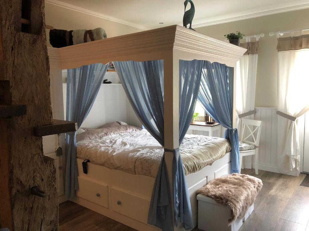 1 dormitorio con cama con dosel y cortinas azules en BnB onder de Blauwe Hemel, en Vlijmen