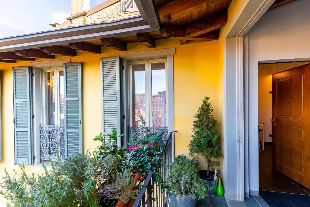 La casa di Fiò في بيرغامو: منزل به جدران صفراء ونباتات على الشرفة